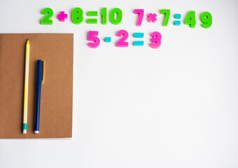 Math exercises, notebook, pen and pencil on a white background, copy space