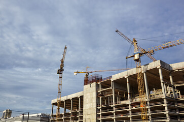 Tower cranes building a house. Concrete building under construction