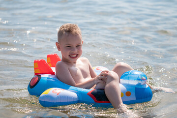 Happy little boy with an inflatable ring swims in the sea