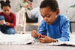 © Drobot Dean - Focused afro american children playing with toys on white carpet at home