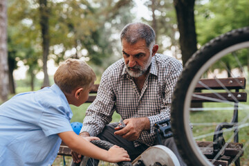 Wall Mural - grandfather and grandson fixing bike