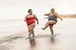 © DisobeyArt - Plus size friends walking on the beach having fun during summer vacation - Focus on faces