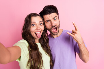 Sticker - Self-portrait of beautiful friends friendship trendy funky couple embracing grimacing showing horn isolated over pink pastel color background