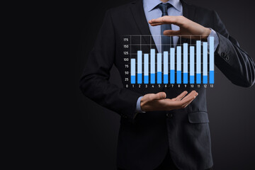 Business man holding holographic graphs and stock market statistics gain profits. Concept of growth planning and business strategy. Display of good economy form digital screen.