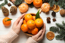 Woman Holding Bowl Of Tangerines At White Wooden Table, Top View. Christmas Atmosphere