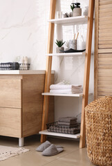 Poster - Soft towels and different toiletries on decorative ladder in bathroom. Interior design