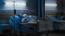 Hospital Ward: Portrait Of Elderly Man Wearing Oxygen Mask Resting In Bed, Struggling To Recover After Covid-19, Sickness, Disease, Surgery. Old Man Fighting For His Life. Dark Blue Sad Shot