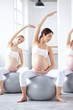 © Roman - Pregnant women sitting on fitball stretching arms