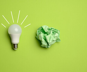 Poster - crumpled colored balls of paper and glass white lamp on green background