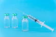 © photobuay - Potential trials stage concept on blue background. Close up Vials with sterile needle syringe. Research and Development, Vaccination.
