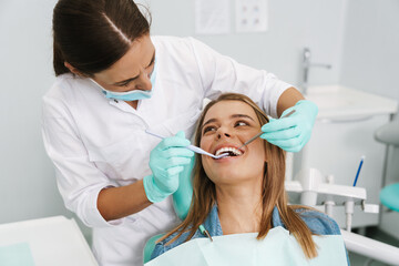 Woman sitting in medical chair while dentist fixing her teeth