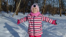 Smiling Child Kid Looking At Camera, Embracing, Fooling Around, Making Faces. Girl Making Hugging Gesture In Winter Snowy Park Forest, Frosty Day Sunset. Children Having Fun At Christmas Holidays Time