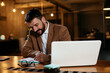 © JustLife - Young businessman using laptop in his office. Happy man working on computer at his workplace.