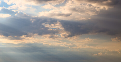 Wall Mural - dramatic dark sky with rays and white clouds at sunset