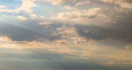 Wall Mural - dramatic dark sky with rays and white clouds at sunset