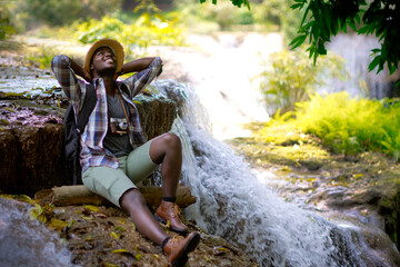 Wall Mural - African traveler man sitting and relaxing freedom with waterfall