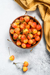 Wall Mural - Yellow ripe cherries in a bowl. White background. Top view