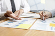 © kamiphotos - Two businessmen are meeting together on company finances, on a table where there is a paperwork for meetings, meetings and plans together for the company to thrive. The concept of corporate finance.
