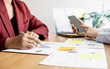 © kamiphotos - Sales are working together to summarize monthly sales to bring in a meeting with executives, female employees using smartphones to view sales data. Sales management concept.