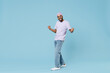 © ViDi Studio - Full length young overjoyed happy fun unshaven black african man in violet t-shirt hat glasses do winner gesture clench fist celebrate scream isolated on pastel blue color background studio portrait.