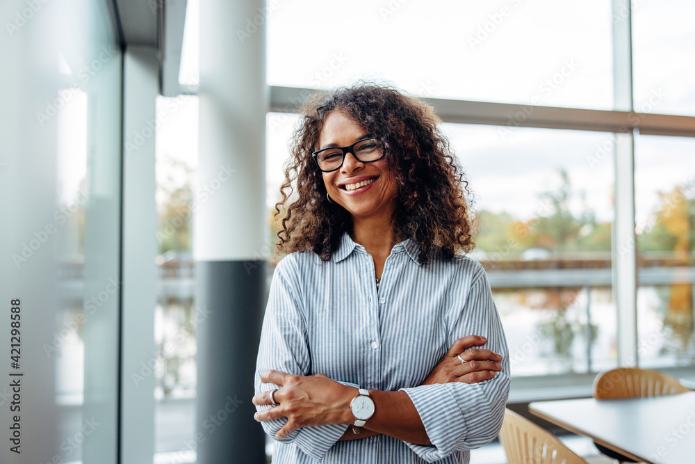 Smiling businesswoman standing in office - obrazy, fototapety, plakaty 