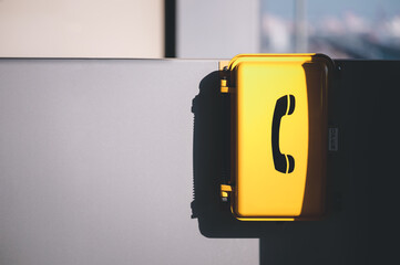 The yellow emergency phone on wall in train station.