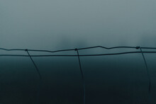 Low Angle View Of Barbed Wire Fence Against Sky