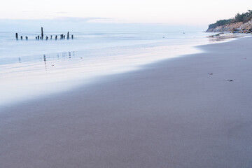 at sunset old wooden poles in the sea