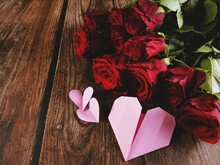 A Bouquet Of Fresh Red Roses And Love Shaped Origami On The Wooden Table Background.