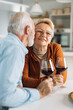© Goran - Loving senior couple communicating while drinking wine at home