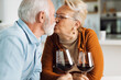 © Goran - Mature couple kissing while drinking wine at home