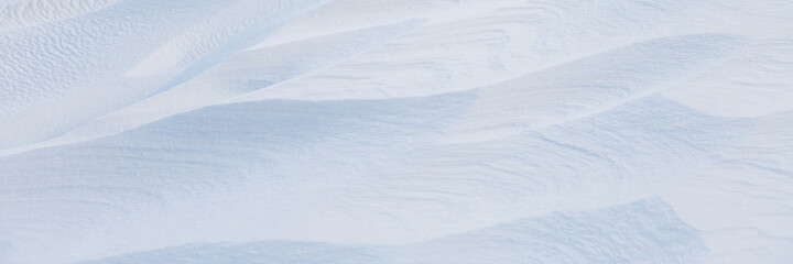 Wall Mural - Beautiful winter background with snowy ground. Natural snow texture. Wind sculpted patterns on snow surface. Wide panoramic texture for background and design.