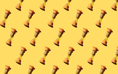 Orange hourglass, seamless pattern on yellow background. minimal concept.The concept of time. Close up