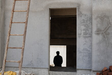 Rear View Of Man Sitting Against Building