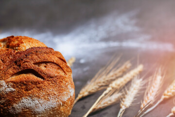 Wall Mural - Fresh homemade bread on a dark counter.  Wheat ticks complete the atmosphere. Copy space for text.