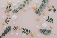 Easter Flat Lay Composition. Luxury White And Gold Easter Eggs Decorated Green And Eucalyptus Leaves On Pink Table. Flat Lay, Top View Copyspace Frame
