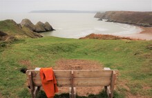 Scenic View Of Bench Overlooking Cliffs And Sea
