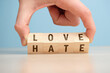 The concept of choosing between love and hate on wooden cubes is turned over by hand.
