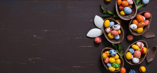 Wall Mural - Banner with chocolate eggs and bunny on wooden table copy space. Happy Easter eggs hunt concept background. View from above