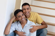 © WavebreakMediaMicro - Portrait of diverse gay male couple sitting on stairs looking at camera and smiling