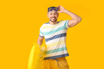 Wall Mural - Handsome man with inflatable mattress on color background