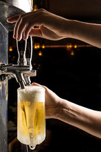 Bartender Hands Pouring A Cold Draft Beer Into A Mug , Black Background. Pilsen