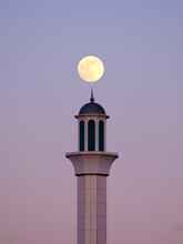 View Of A Full Moon Rising Above A Tower Against Sky During Sunset