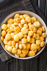 Wall Mural - Pickled lupine beans close-up in a bowl on the table. Vertical top view from above