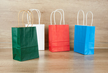 Wall Mural - Colorful paper shopping bags on the floor against a wooden wall background