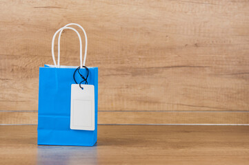 Wall Mural - Shopping bag with a blank tag on wood table against wooden wall