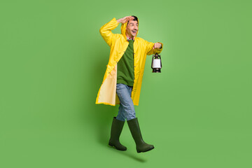 Poster - Full size photo of young happy excited smiling man go walk look copyspace hold lamp isolated on green color background