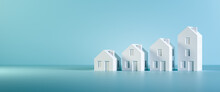 Which Size Of House Can You Afford? Concept Shot: Four Differently Sized Models Of Houses On A Blue Background. Copy Space Available, Web Banner Format