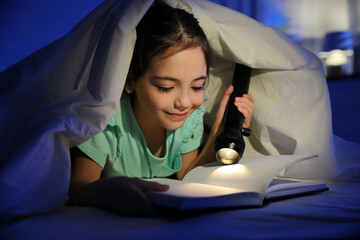 Canvas Print - Little girl with flashlight reading fairy tale in dark bedroom