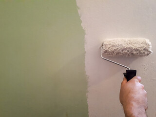 Closeup shot of a man painting the wall with a paint roller